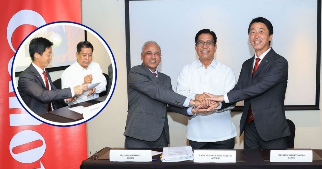 A group of executive representatives from AFPSLAI and Canon Marketing Philippines participate in a handshake to signify a partnership for the Records Digitization Project, with documents and a presentation screen in the background.