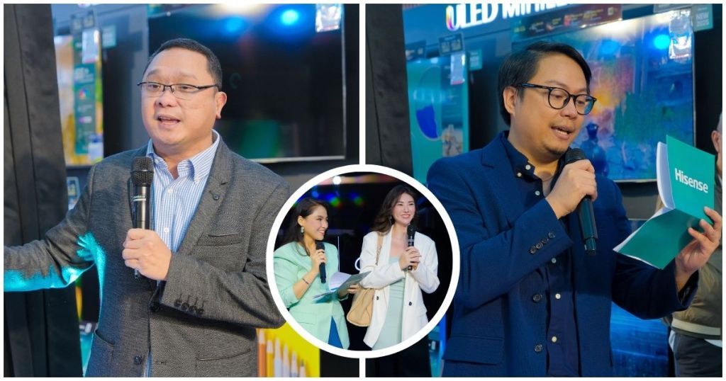 Two presenters speaking at the Hisense 116-inch Class UX Series RGB-MiniLED TV launch event, with a crowd and product displays in the background.