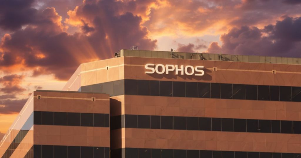Exterior view of a modern building with a sign reading 'SOPHOS', set against a dramatic sunset sky.