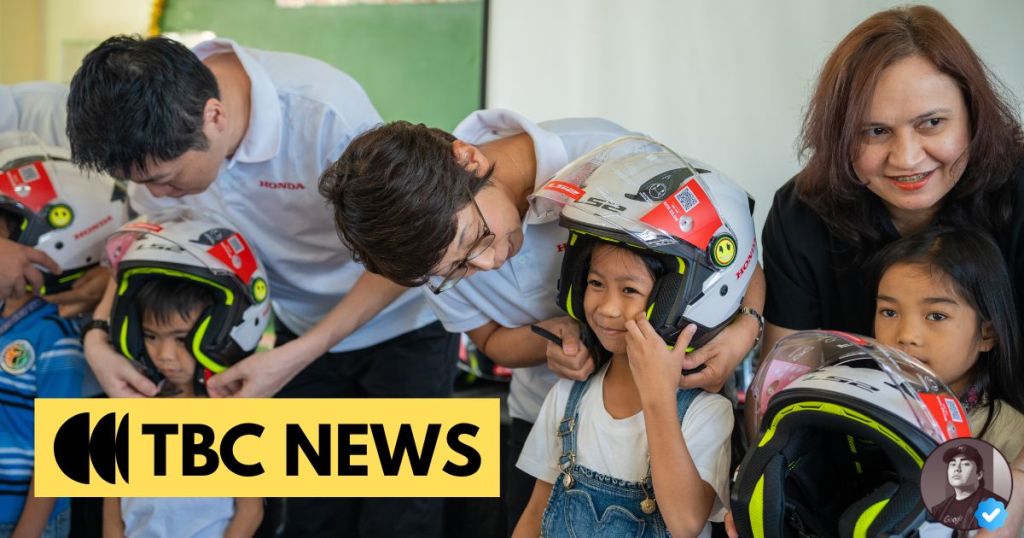 Children receiving safety helmets with adults assisting them at an event, showcasing a focus on safety awareness.