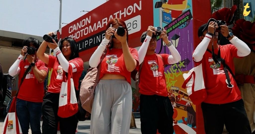 Group of photographers in red shirts holding cameras at a photography event with a colorful backdrop.