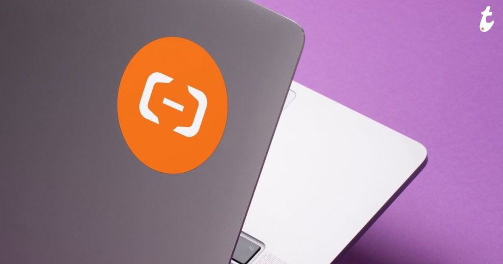 Laptop with a bright orange logo on the lid, set against a purple background.