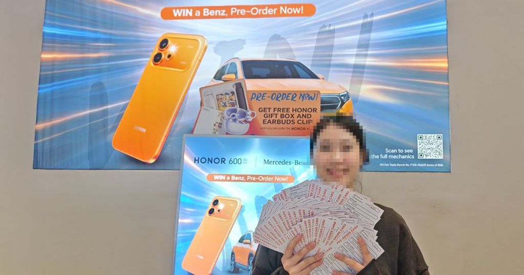 A woman holding a large stack of promotional tickets in front of a colorful advertisement featuring an orange smartphone and a Mercedes-Benz car, promoting a pre-order event.
